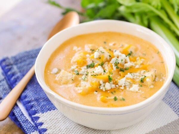 A bowl of buffalo chicken soup topped with bleu cheese and herbs.