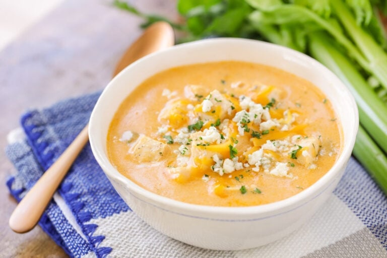 A bowl of buffalo chicken soup topped with bleu cheese and herbs.