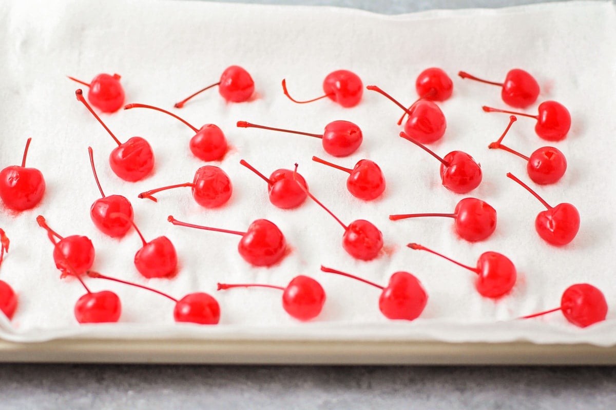 Maraschino cherries drying on paper towel lined cookie sheet.