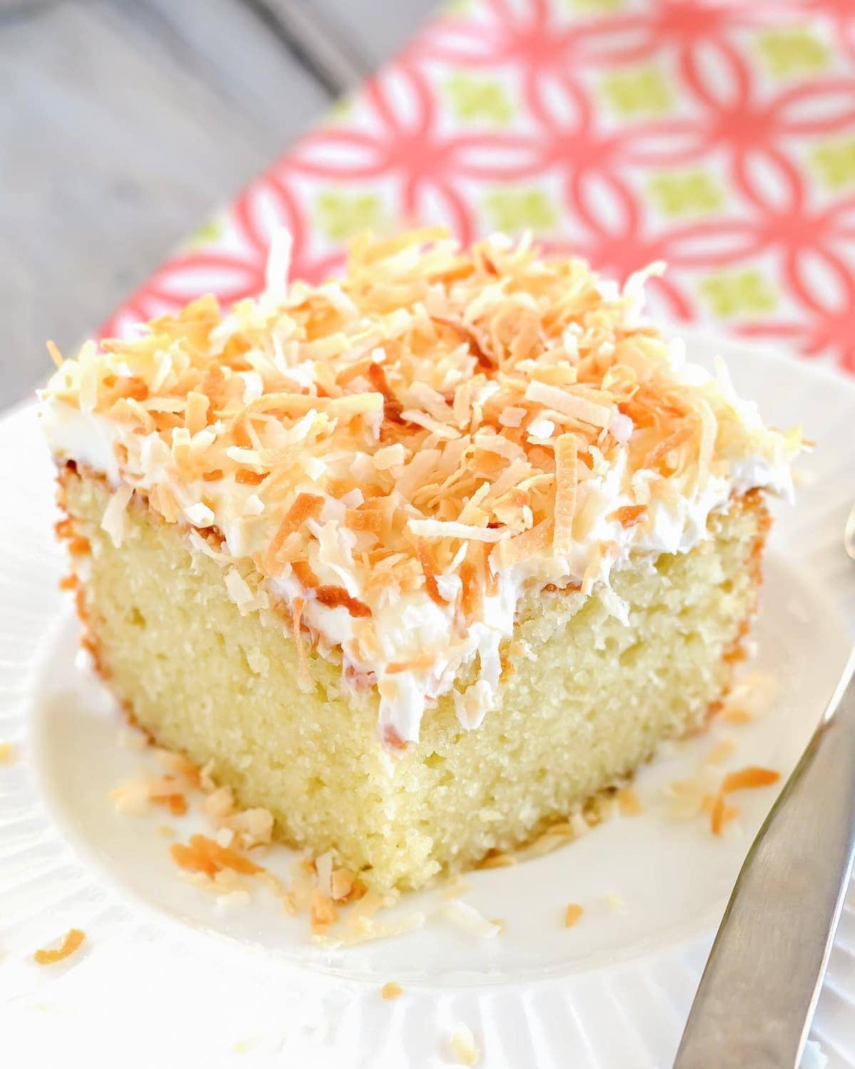 A square slice of easy coconut cake on a white plate.