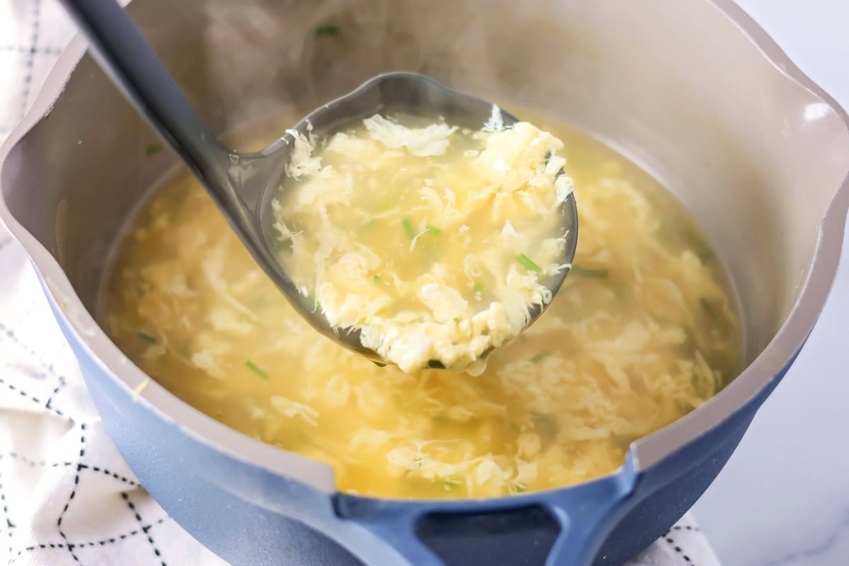 Ladle of egg drop soup scooped out of pot.