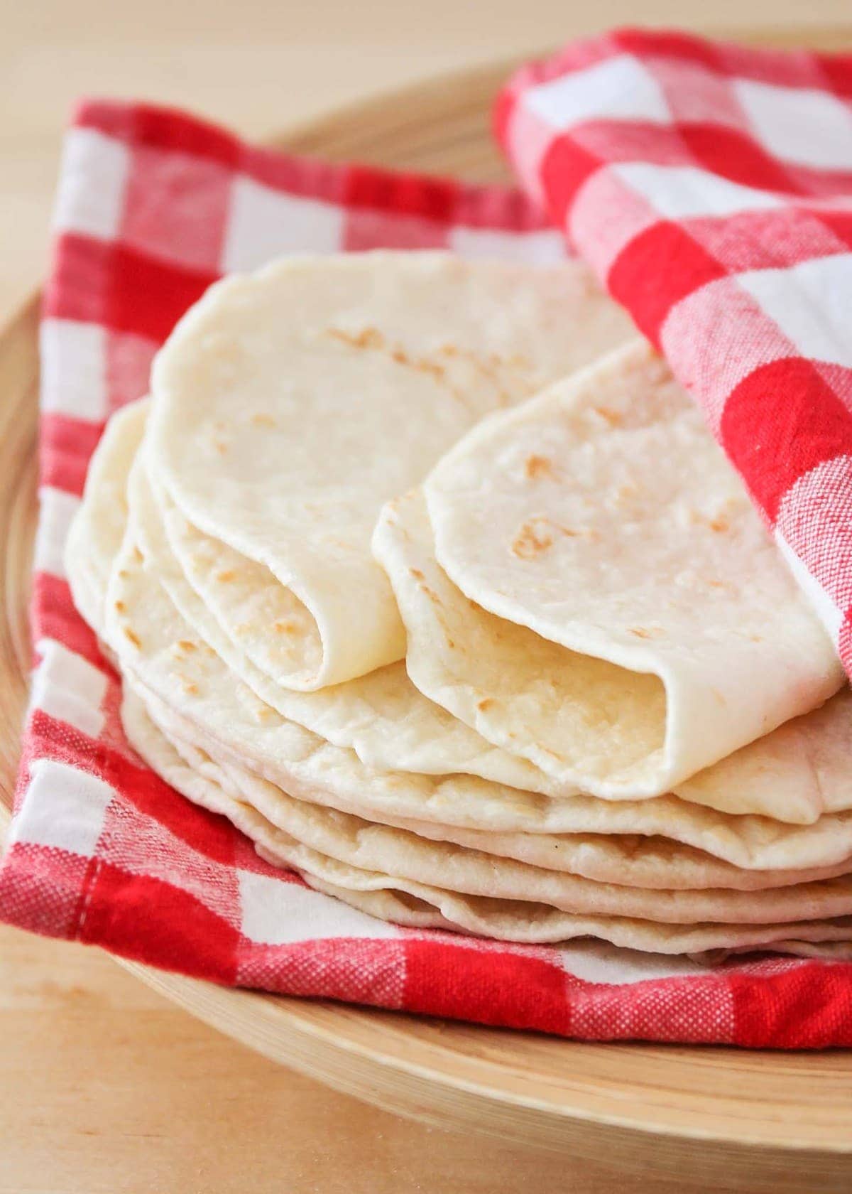 Homemade Flour Tortillas stacked on a plate.