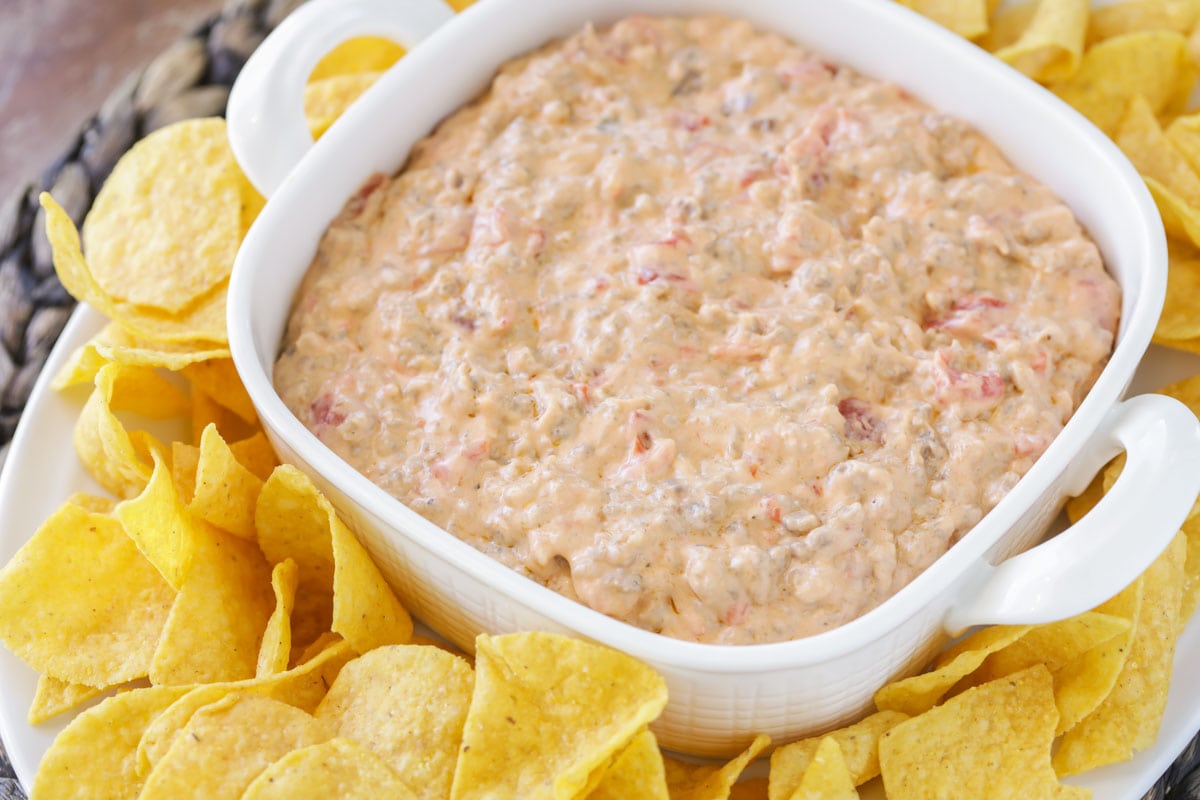 Sausage cream cheese dip in a white serving bowl surrounded with chips