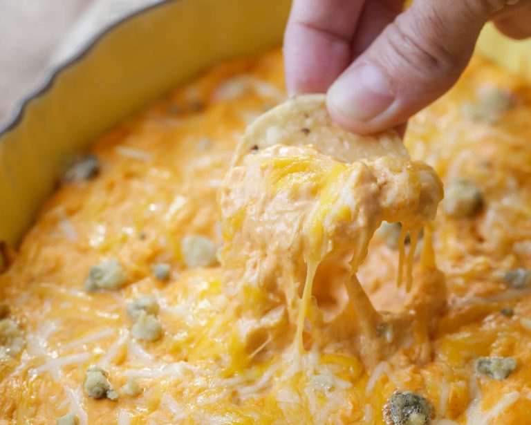 Buffalo chicken dip recipe being scooped onto a chip.