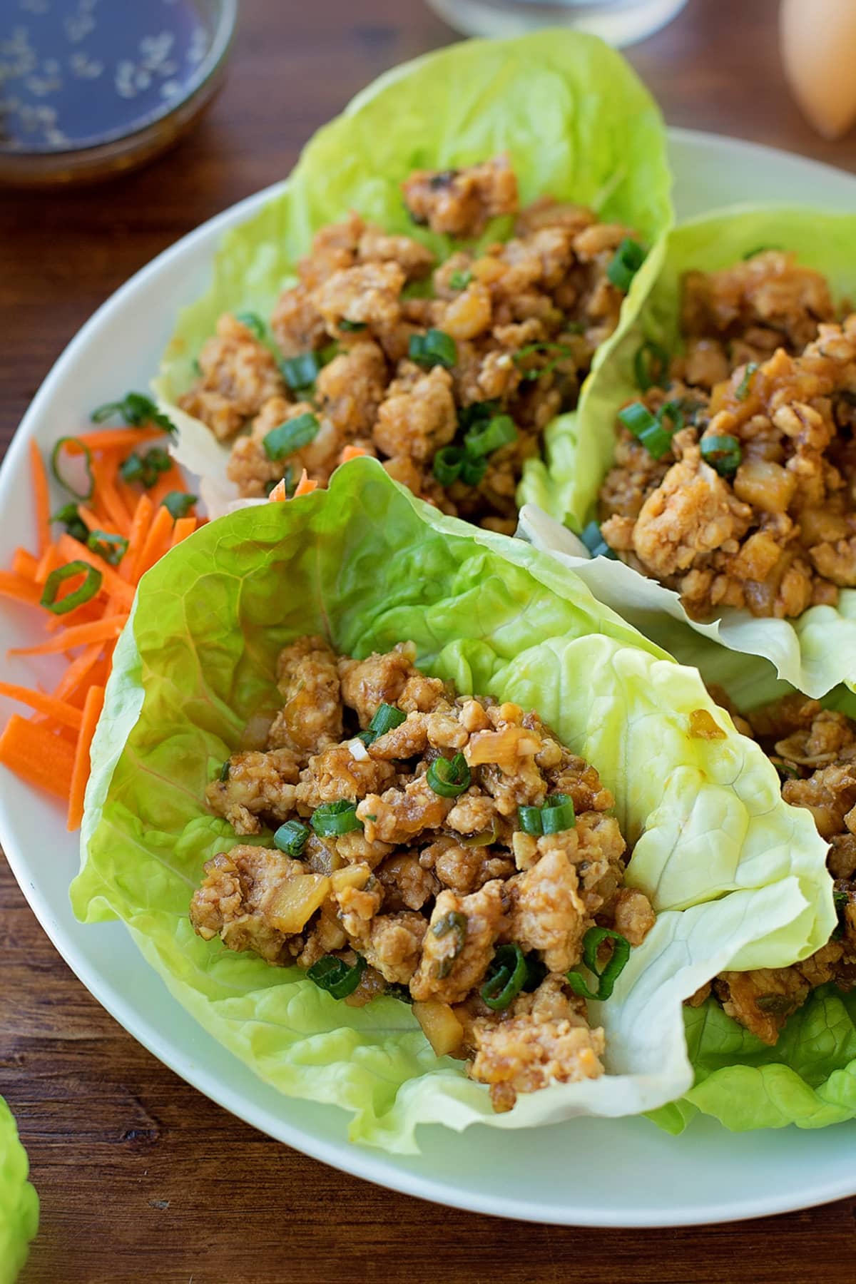 Three homemade PF Changs Chicken Lettuce Wraps on a white plate.