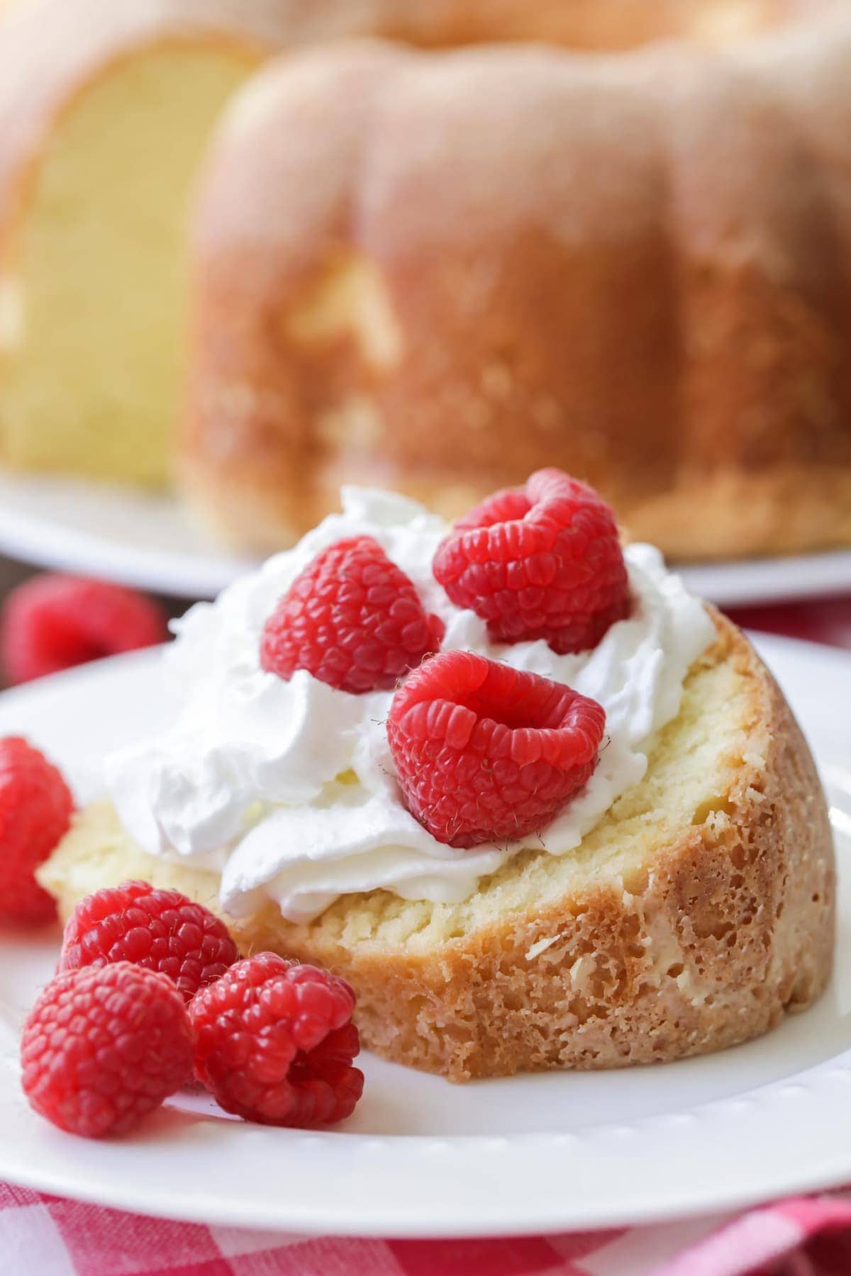 Cream Cheese Pound Cake on a plate topped with whipped cream and raspberries.
