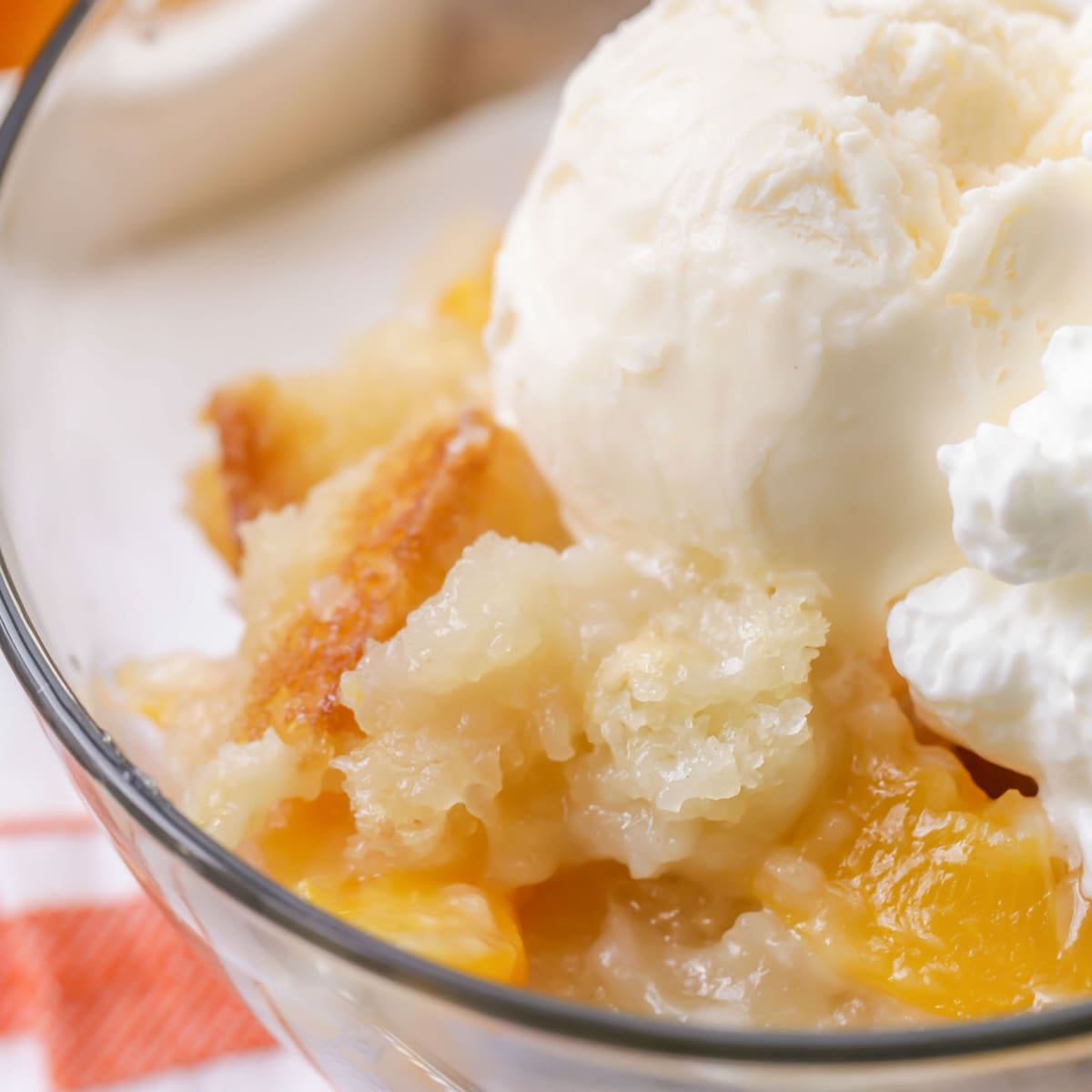 Close up of Peach Cobbler topped with vanilla ice cream in a bowl.