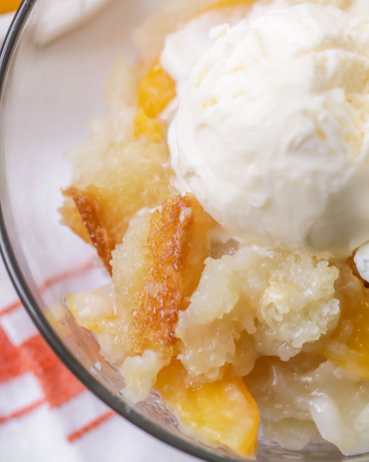 Easy Peach Cobbler Recipe topped with vanilla ice cream in a bowl.