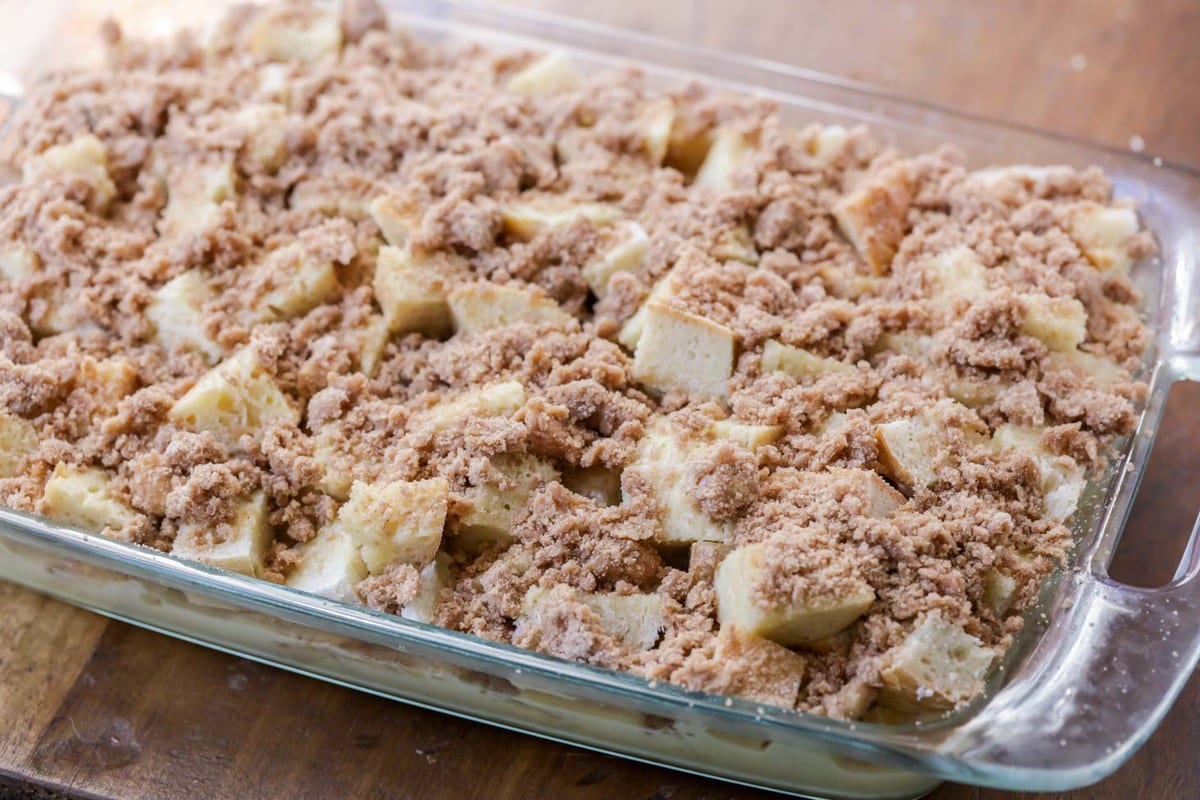 Cubes of bread topped with brown sugar mixture in a glass baking dish for French Toast Bake.