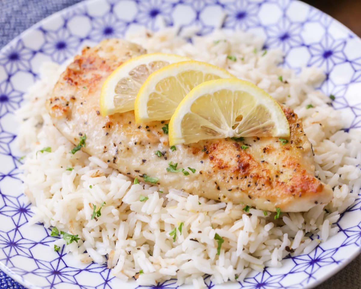 Lemon pepper chicken served over a bed of rice and topped with lemon slices.