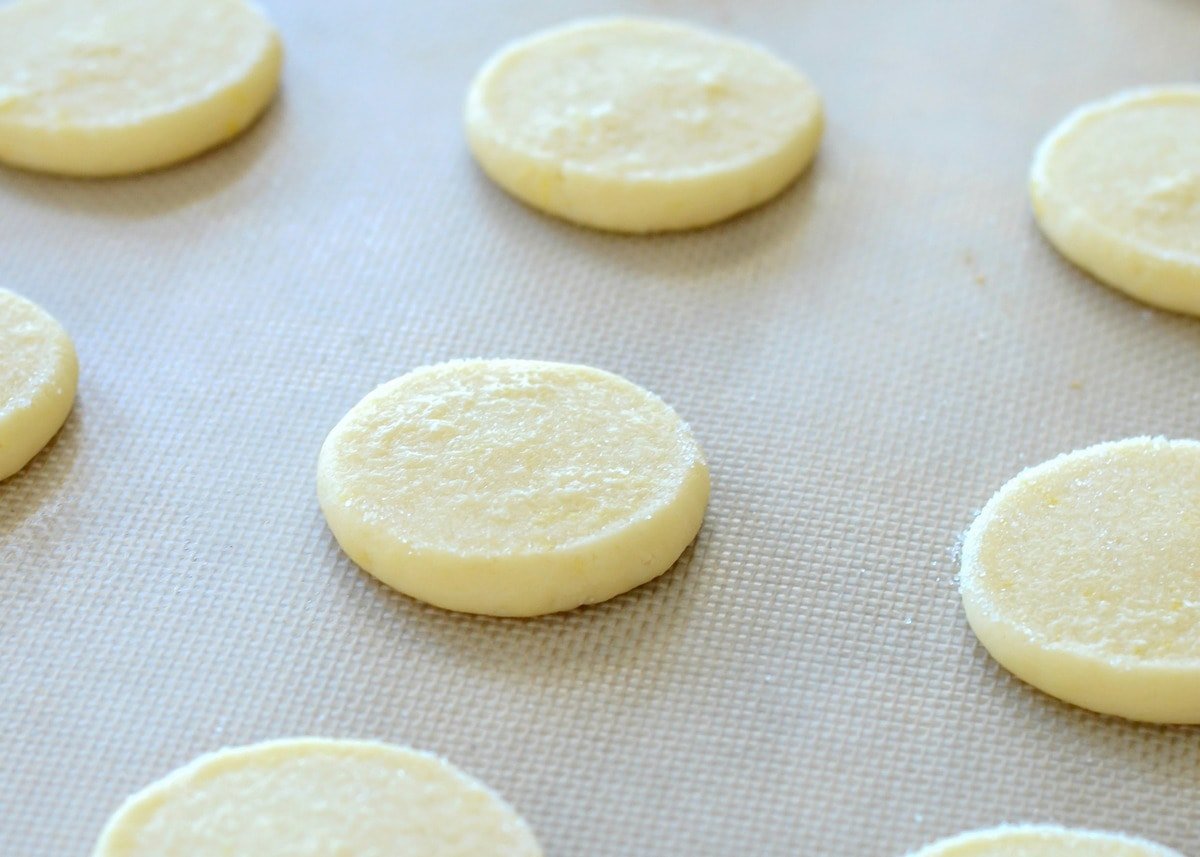 Lemon sugar cookies flattened on baking sheet.