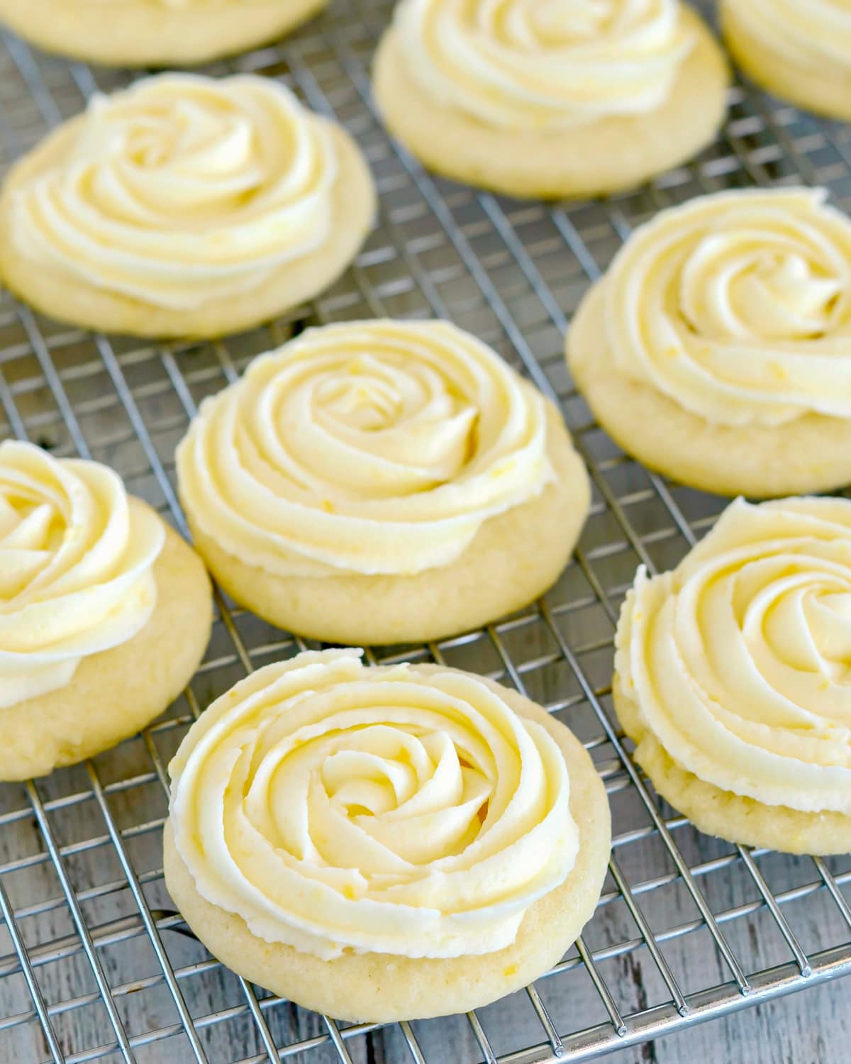 Frosted lemon sugar cookies lined up on a cooling rack. 