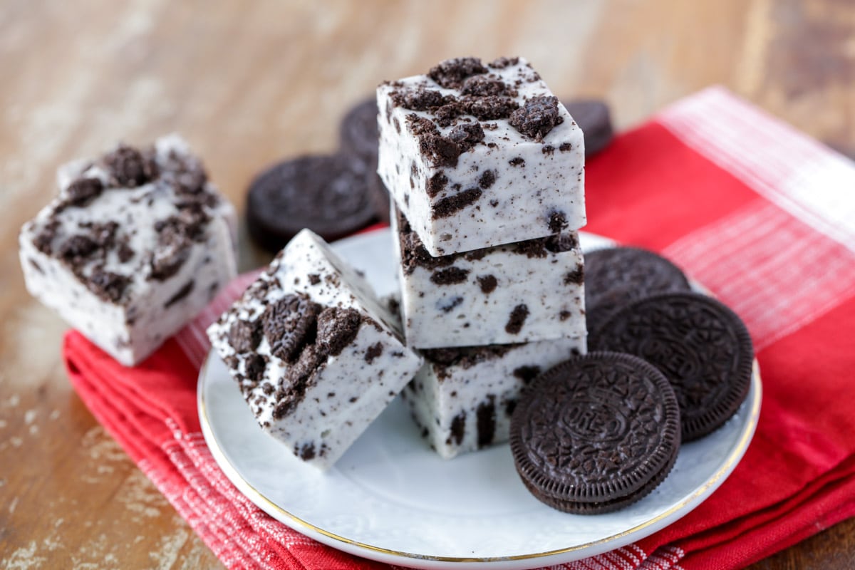 Easy white chocolate cookies and cream fudge is FILLED with crushed Oreos and creamy marshmallow fluff that will satisfy any Oreo lover! Pieces of cookies and cream fudge stacked on a white plate