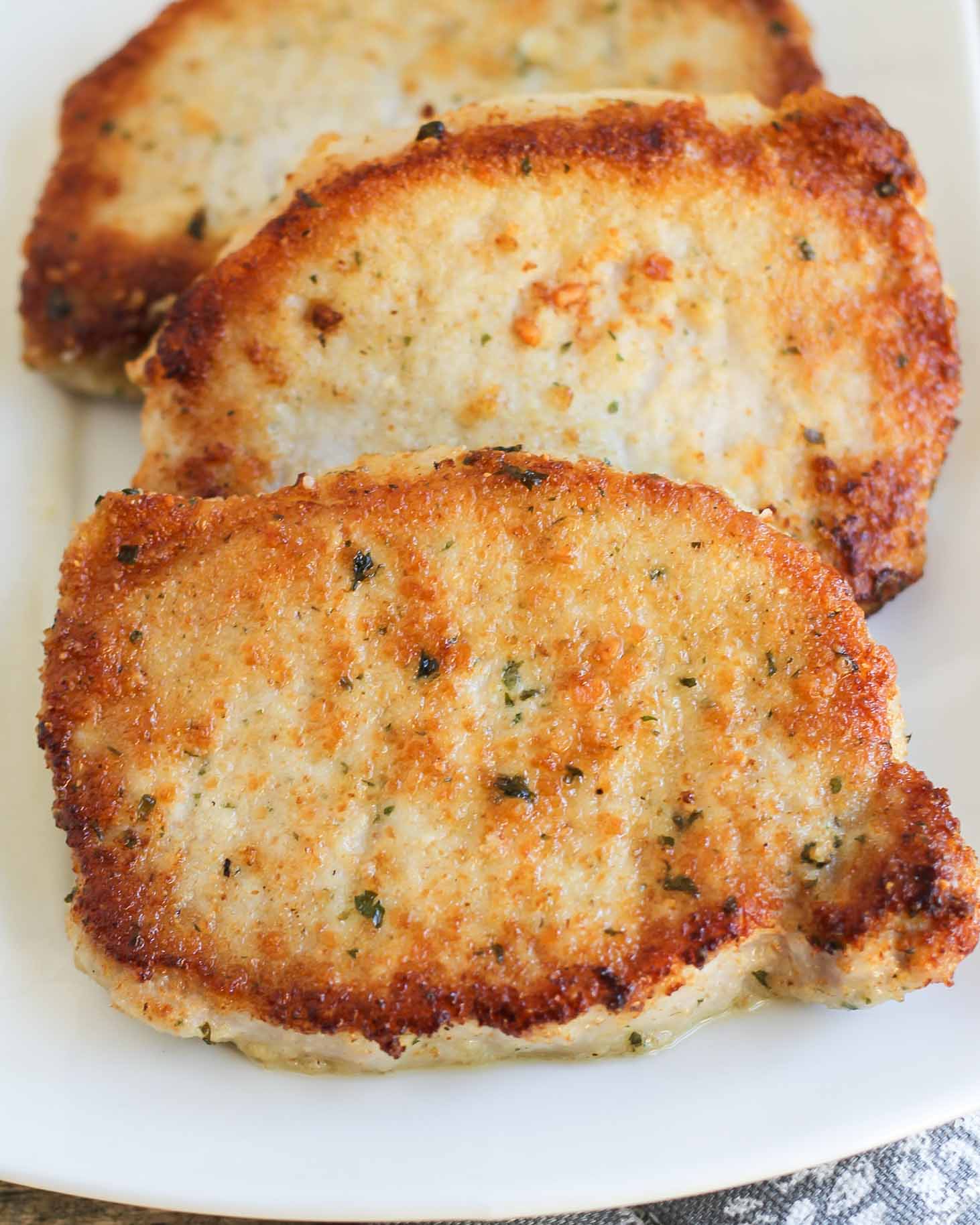 Three Parmesan Crusted Pork Chops on a white plate