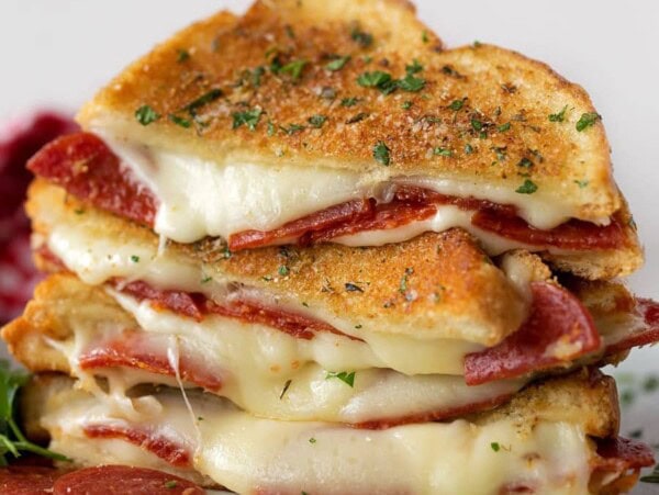 Two pizza grilled cheese sandwiches stacked on a plate.