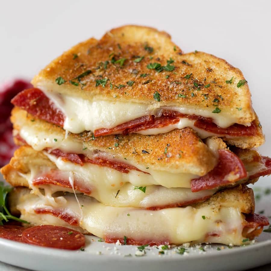 Pizza grilled cheese sandwiches cut in half and stacked on a plate