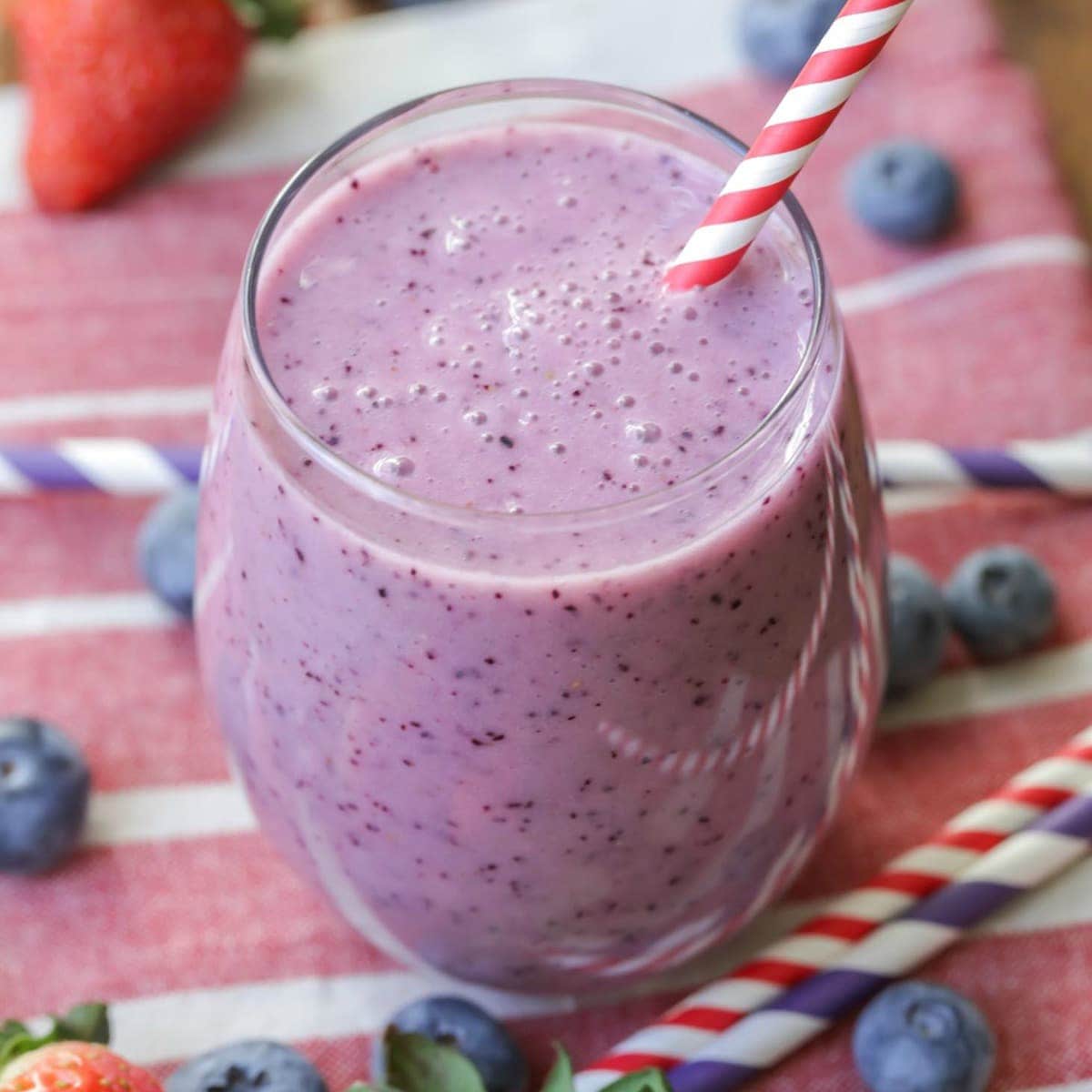 Strawberry Blueberry Smoothies served in a glass with a red and white straw.