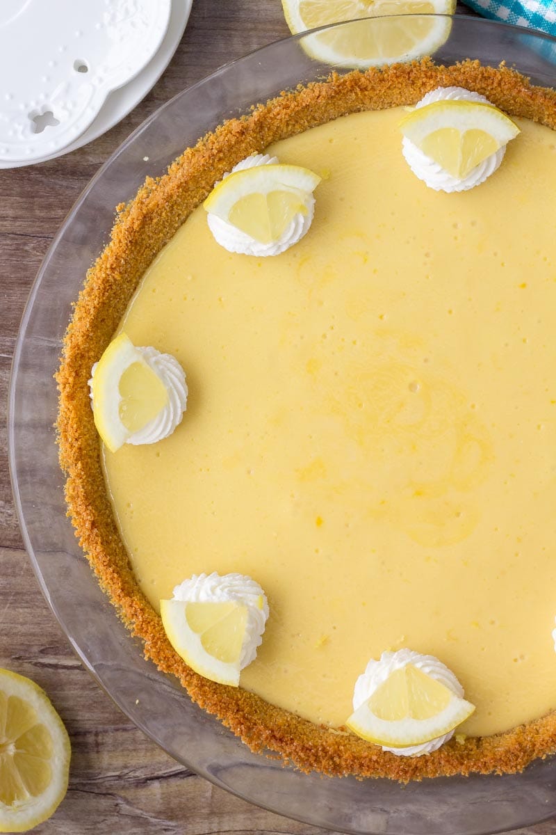 Lemon icebox pie in a glass pie dish topped with whipped cream.