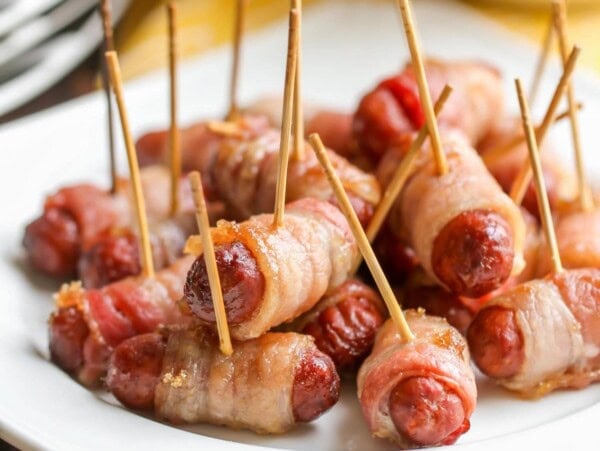 Bacon wrapped smokies on a platter stuck with toothpicks.
