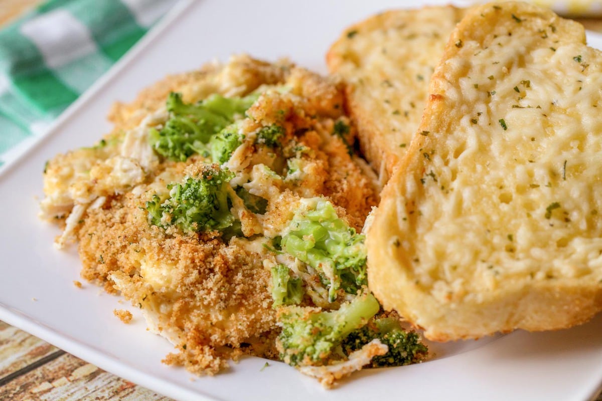 Broccoli and Cheese Casserole with garlic bread on dish.