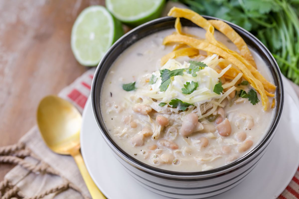 Bowl of white chicken chili topped with shredded tortilla crisps.