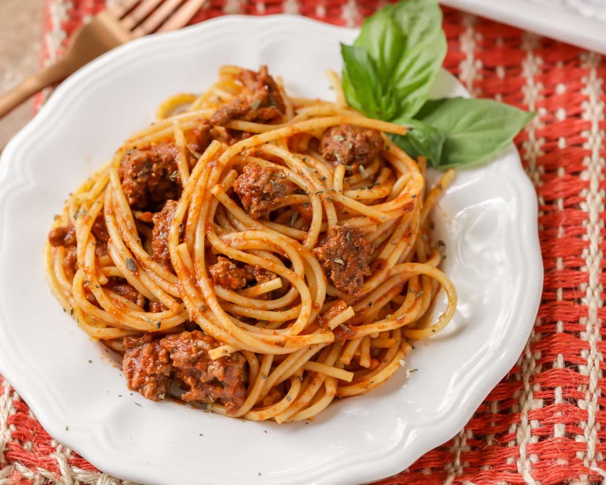 Spaghetti served on a plate with fresh basil.