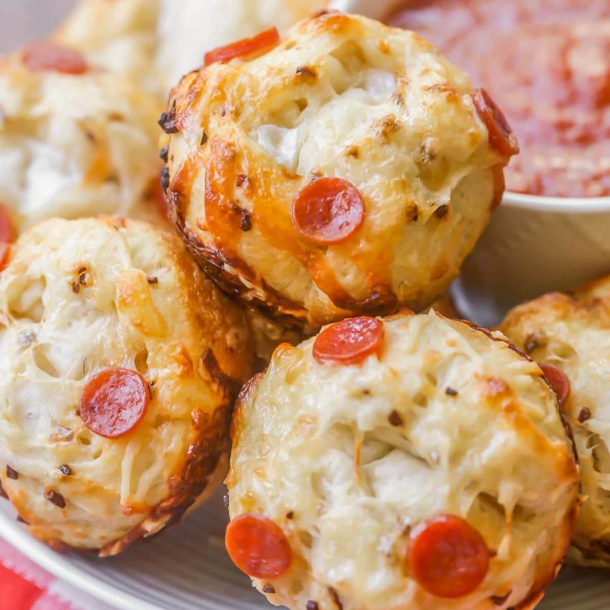 Super Bowl Appetizers - Cheesy Pizza Muffins with a side of marinara sauce on a white plate. 