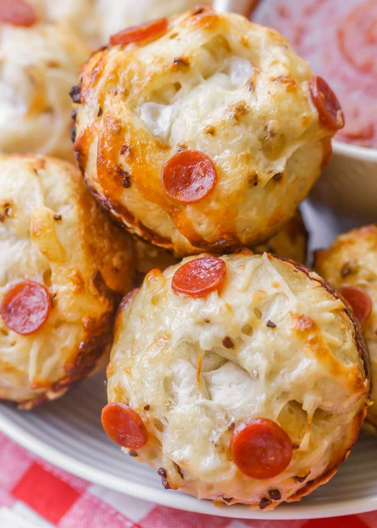 Pizza muffins on a plate with a side of marinara sauce. 
