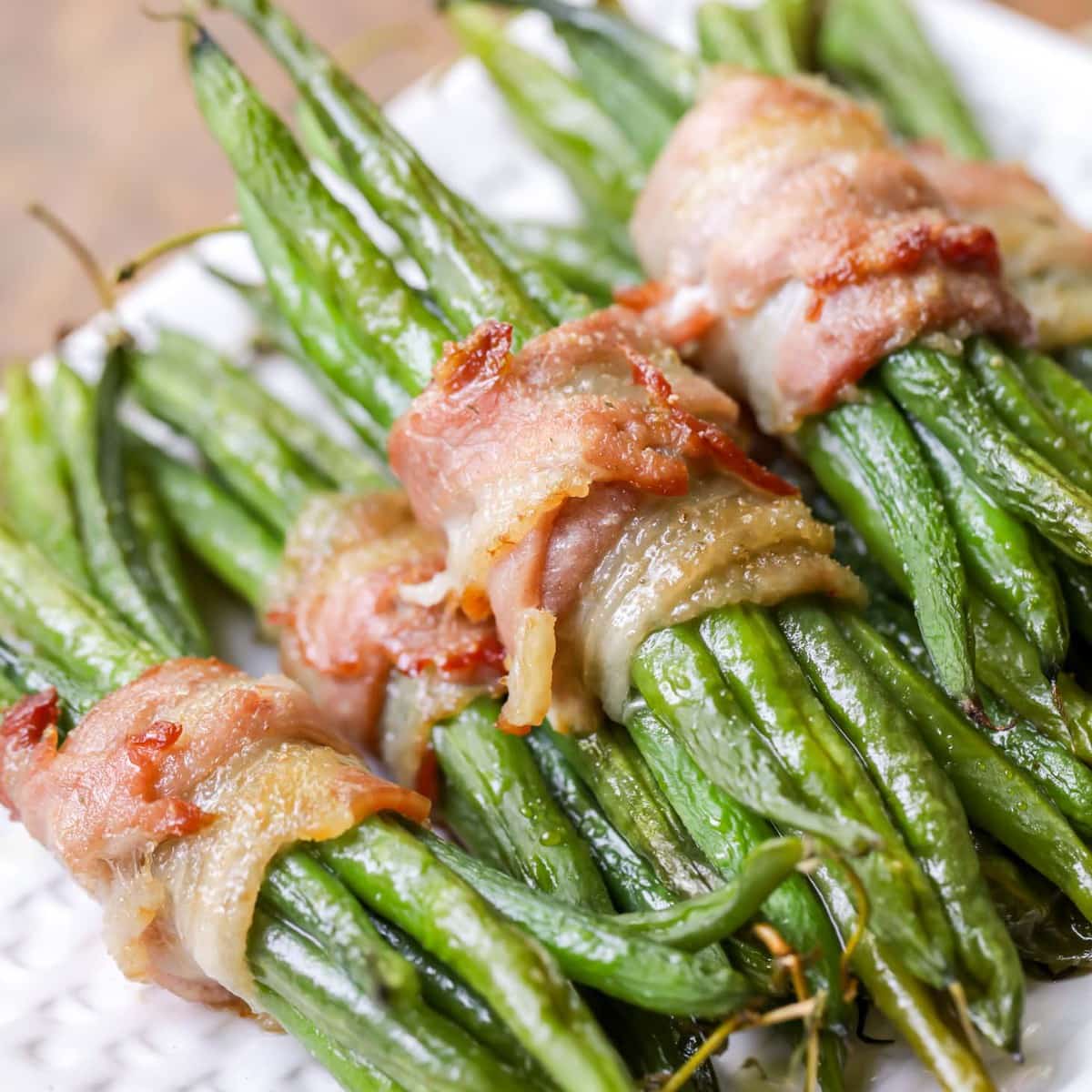 Bacon wrapped green beans on a white serving platter.