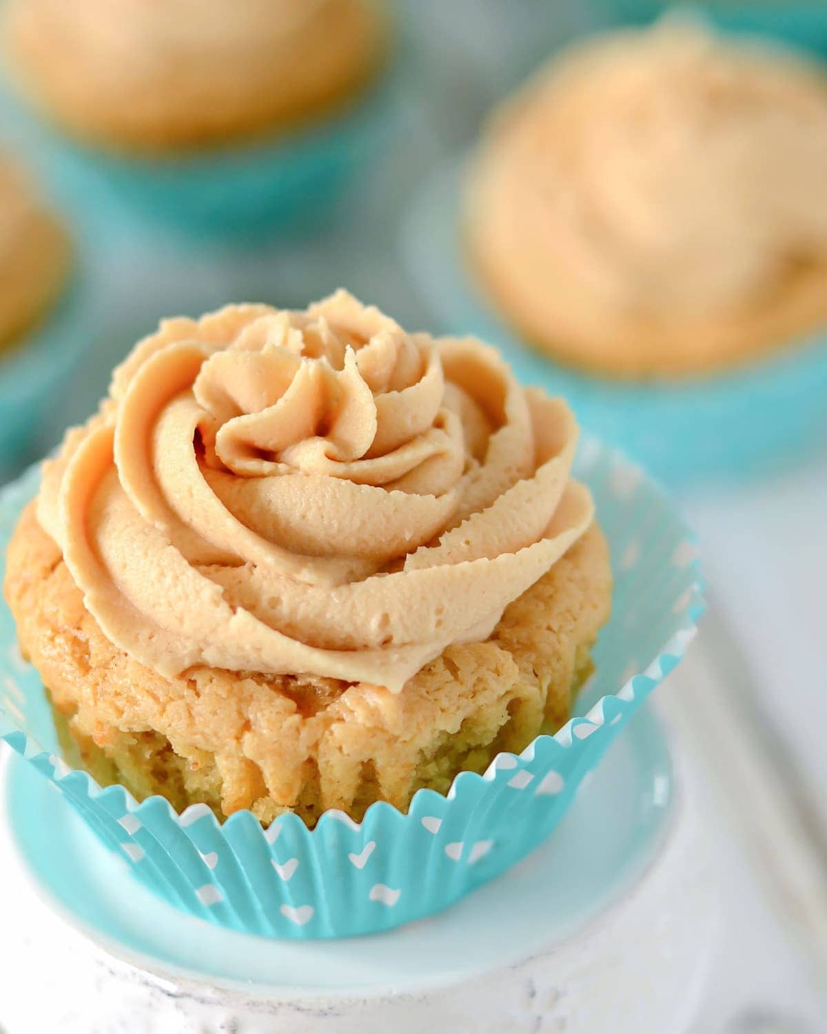 Peanut butter cupcakes with peanut butter frosting on a white plate.