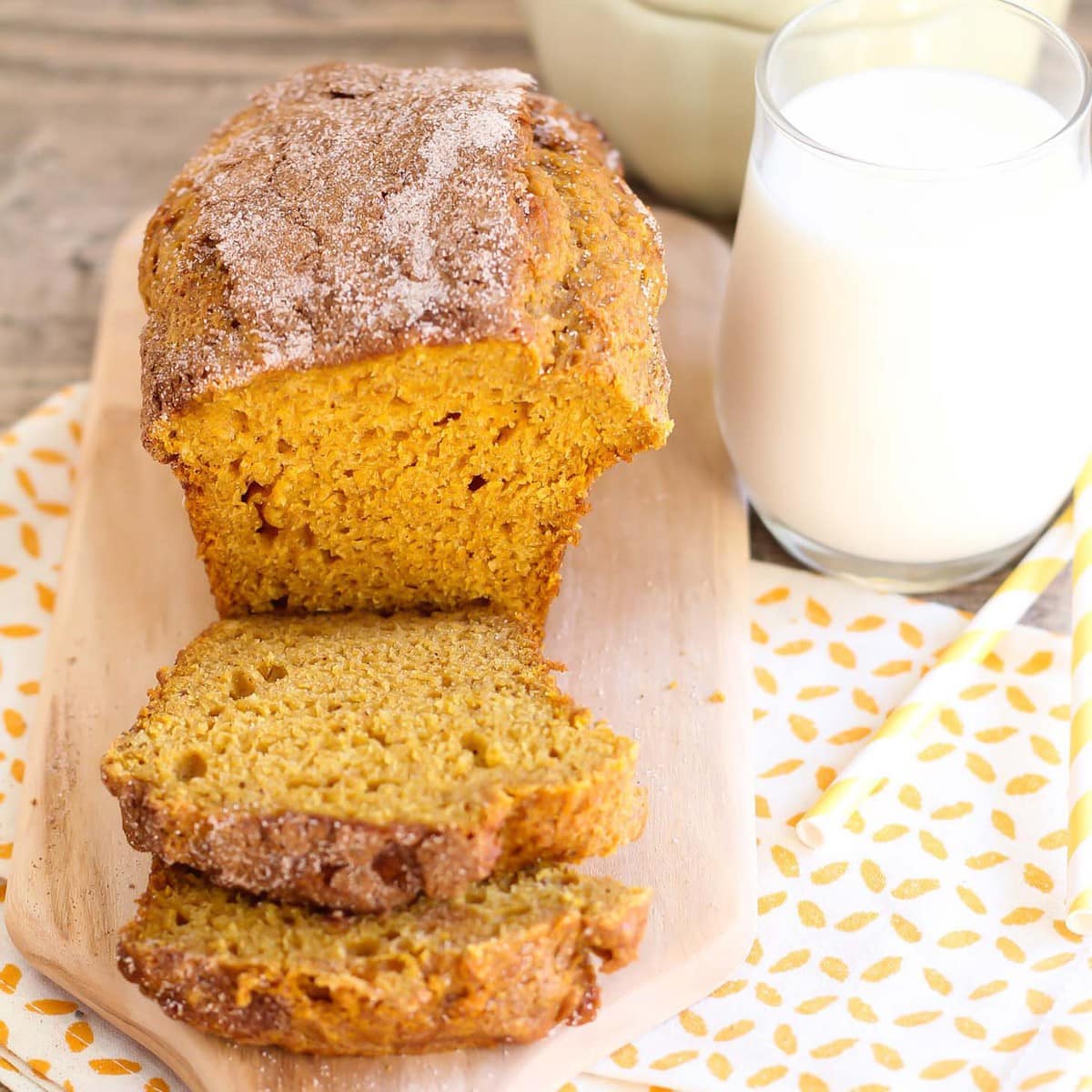 Pumpkin Bread sliced on a cutting board next to a glass of milk.