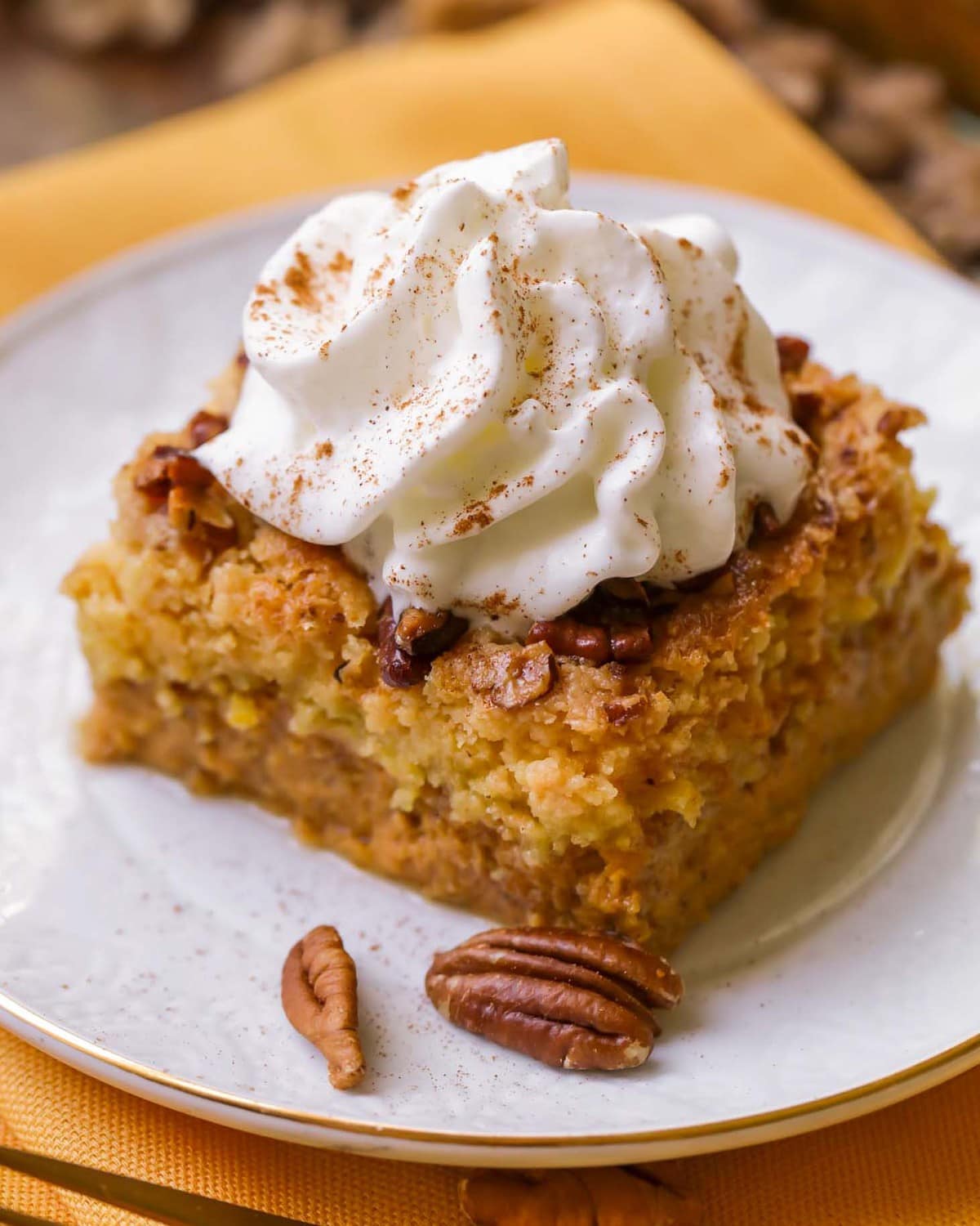 Close up of Pumpkin Dump Cake Recipe topped with fresh whipped cream.