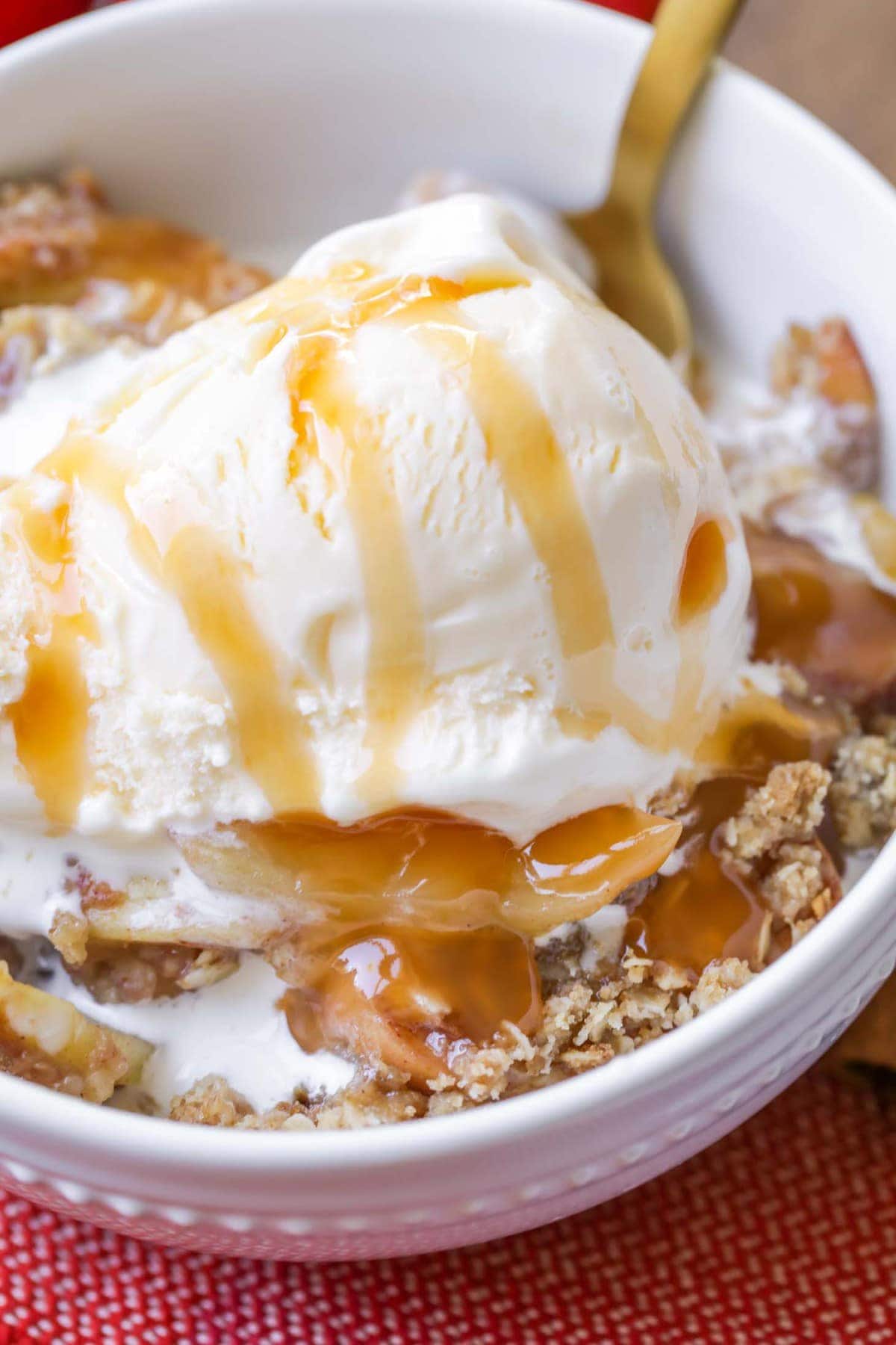 Easy Apple Crisp topped with vanilla ice cream and caramel syrup in a bowl
