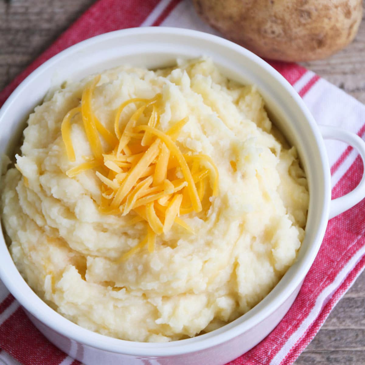 Crockpot side dishes - slow cooker mashed potatoes topped with cheddar cheese.