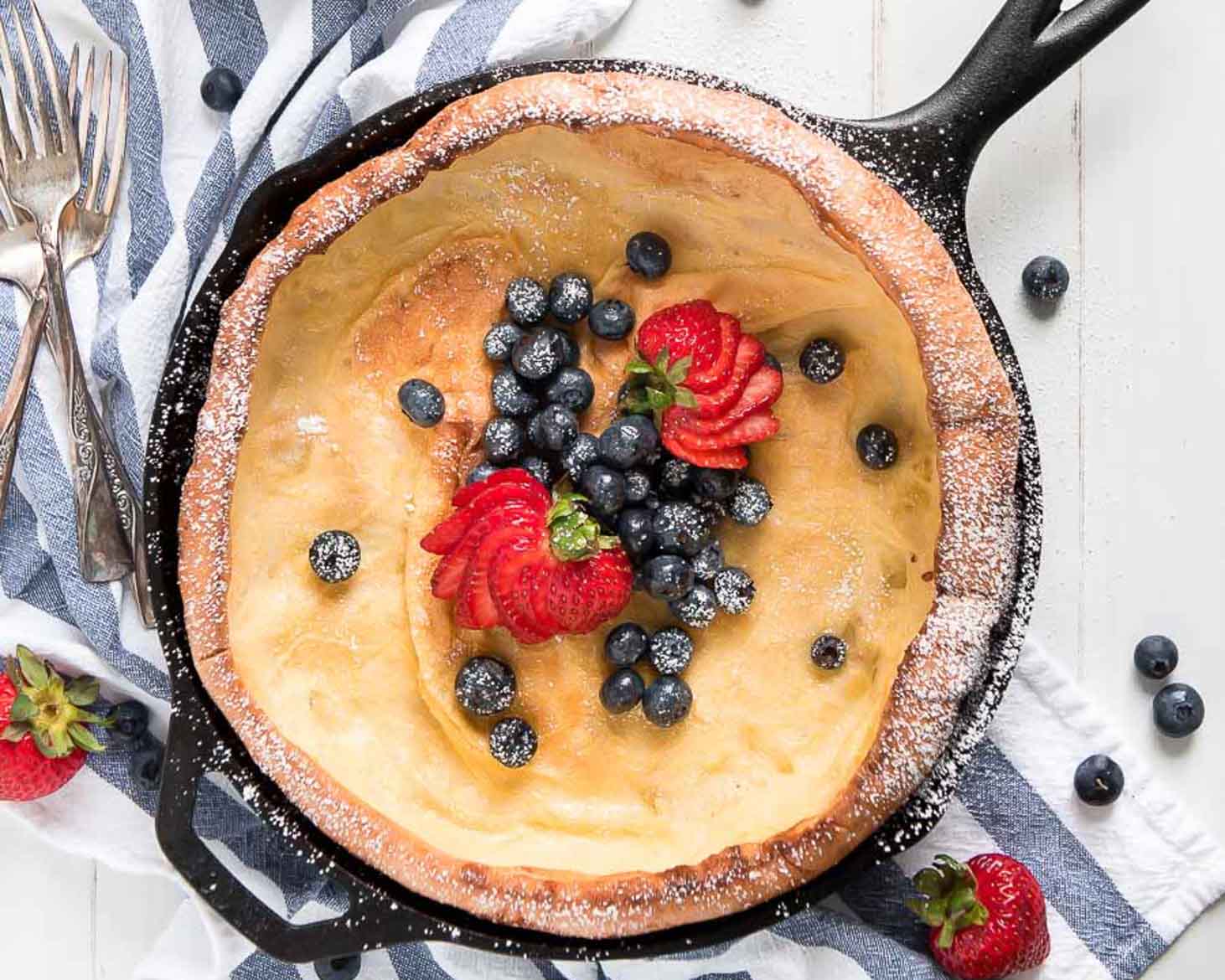 A pancake in a cast iron skillet topped with fresh berries.