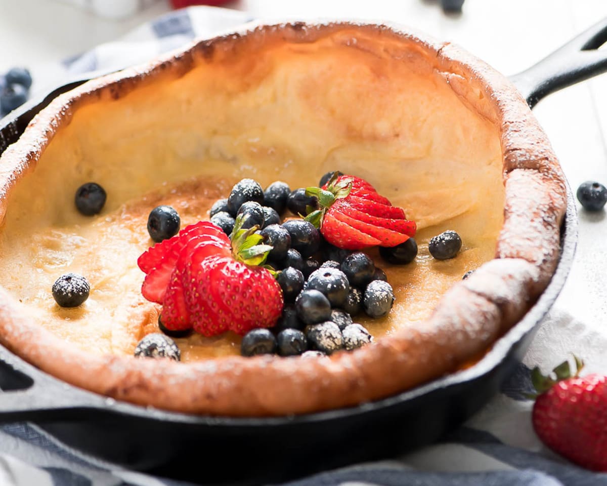 Dutch baby pancake in a cast iron skillet topped with fresh berries.