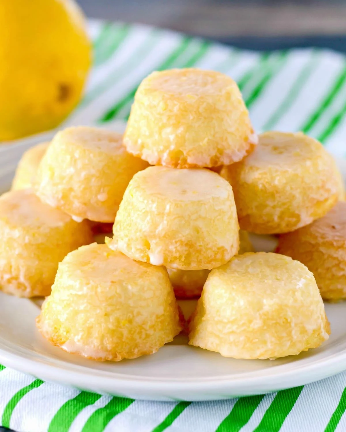 Mini Lemon Drop Cakes glazed and stacked on a white plate