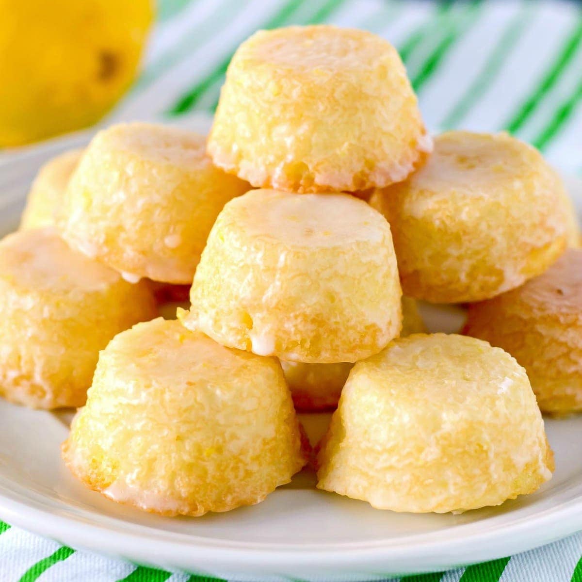 Stacked and glazed mini lemon drop cakes on a white plate