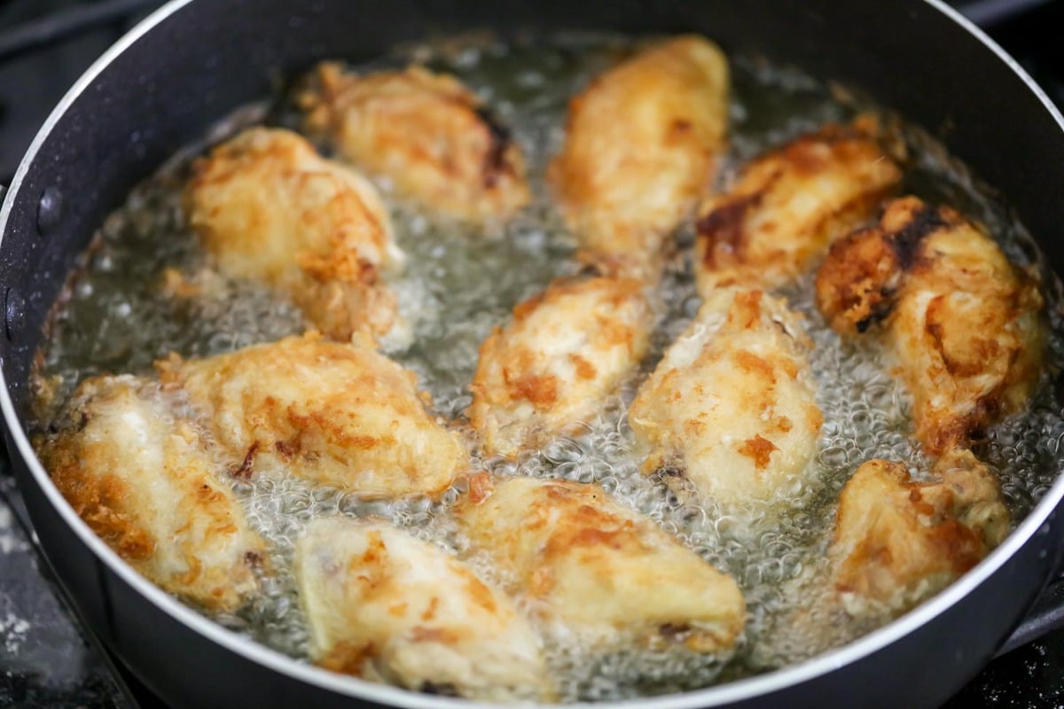 Frying homemade teriyaki chicken wings in a pan.