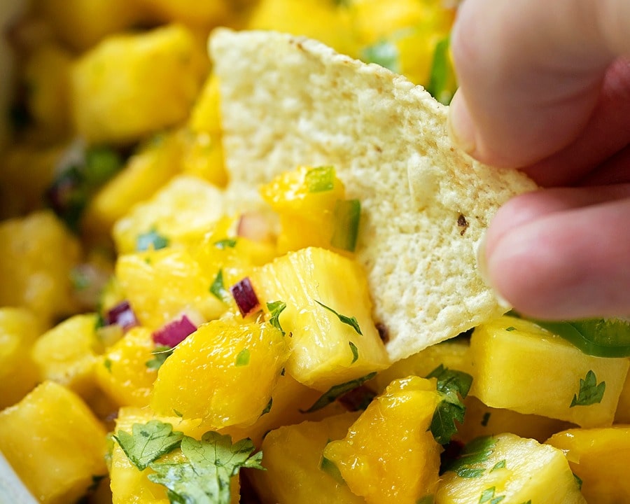 Mango Salsa with pineapple scooped onto a tortilla chip.