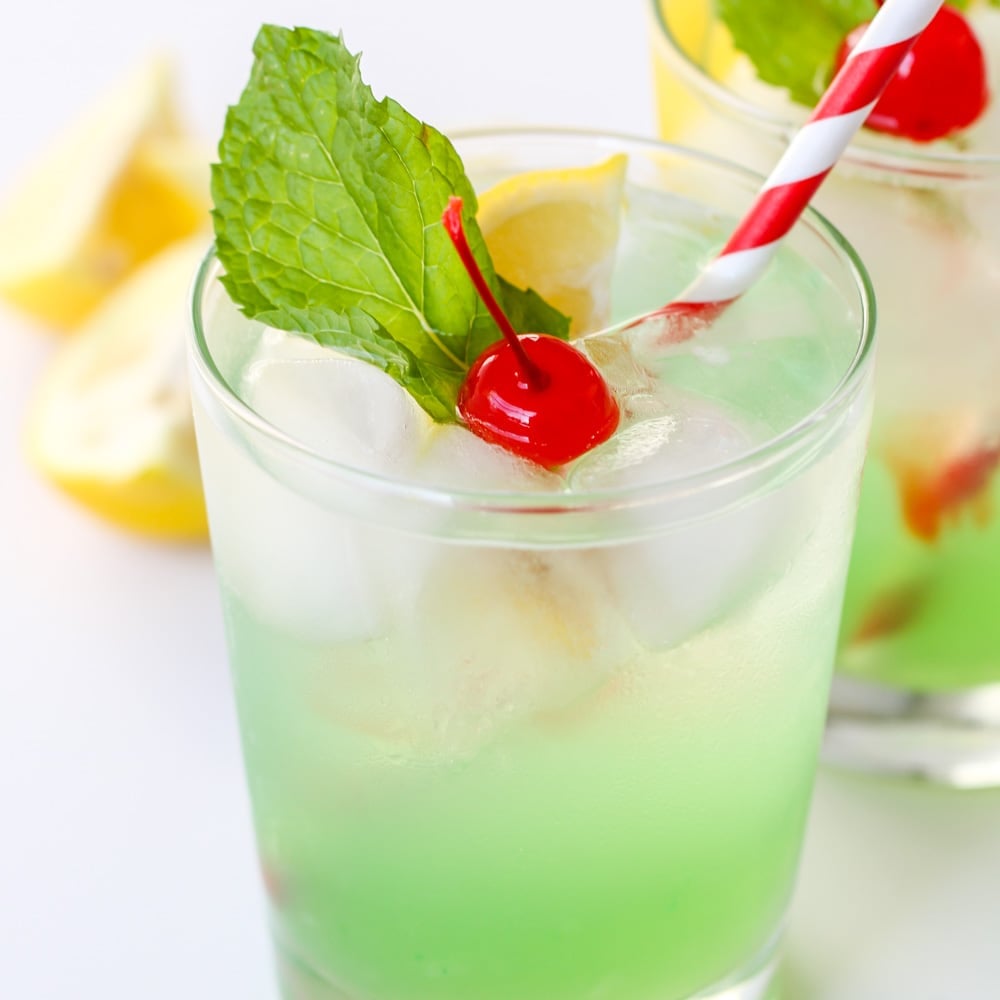 A non alcoholic mint julep topped with a cherry and mint leaf.