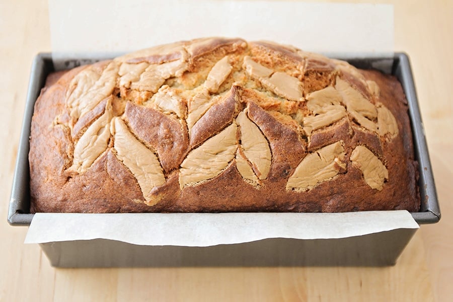 A loaf of peanut butter banana bread in a parchment lined metal bread pan. 