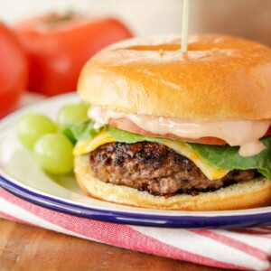 A ranch burger served on a plate with fresh fruit.