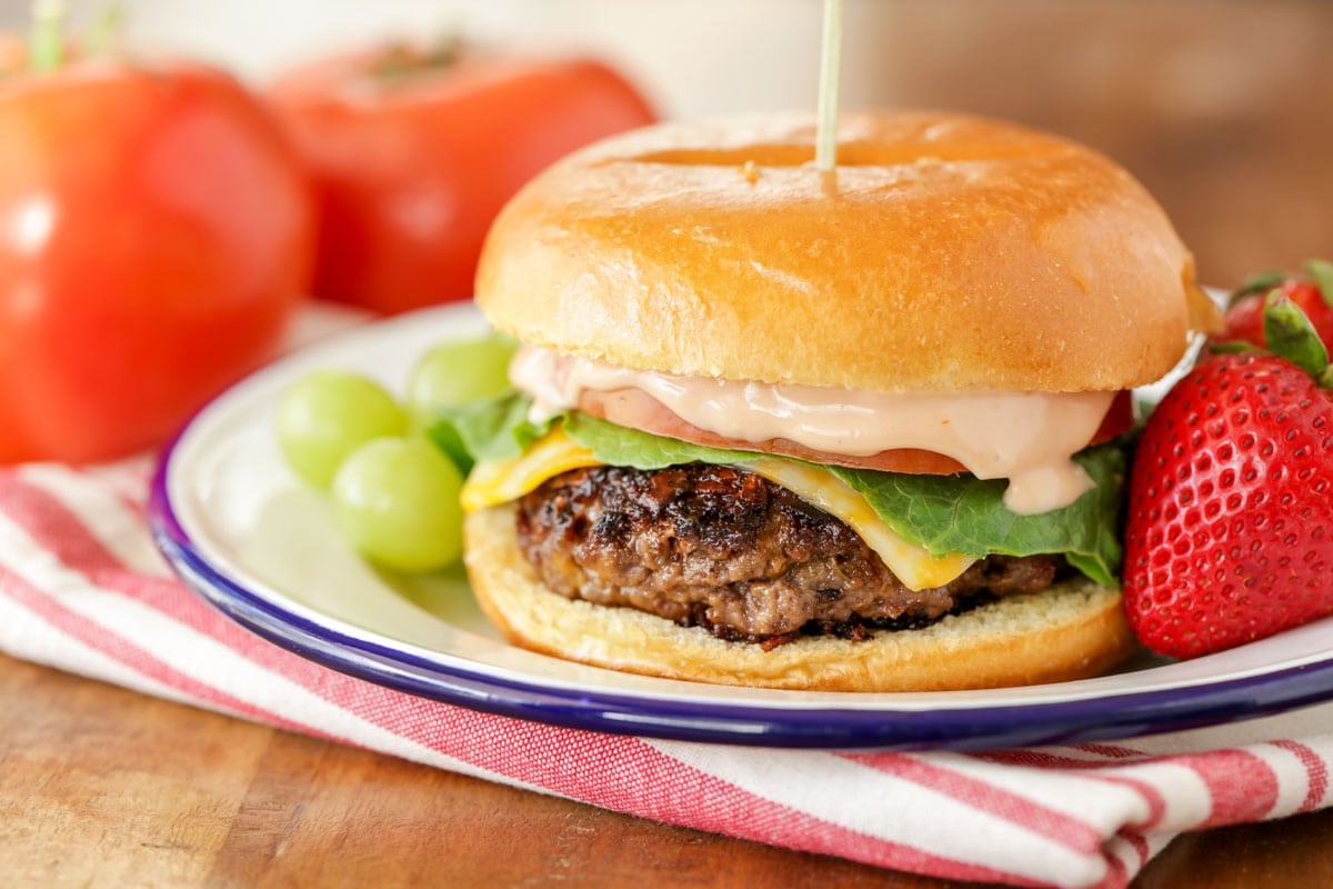 Grilled turkey burger on a plate with strawberries and grapes. 