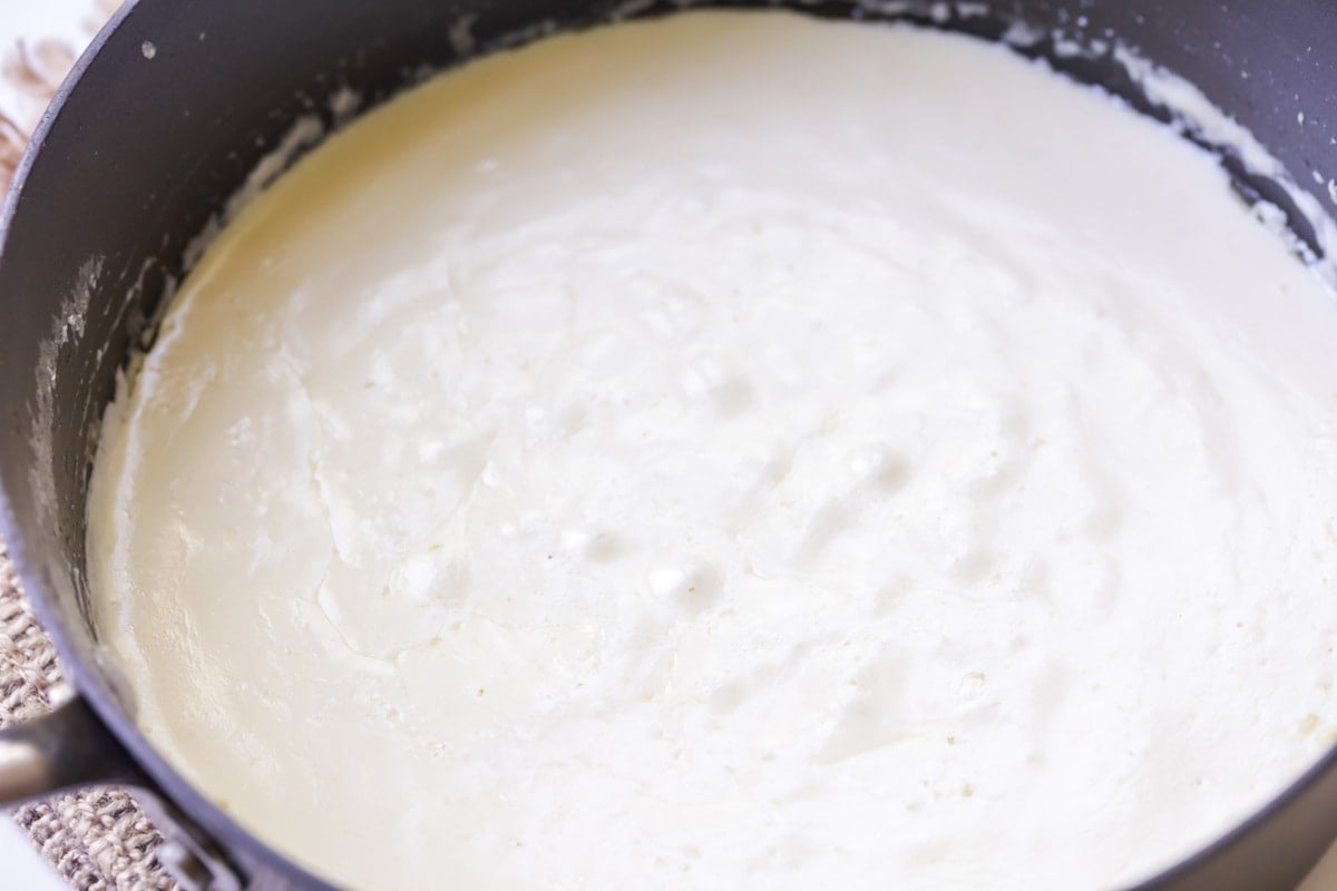 A cream sauce cooking in a pan on the stove.