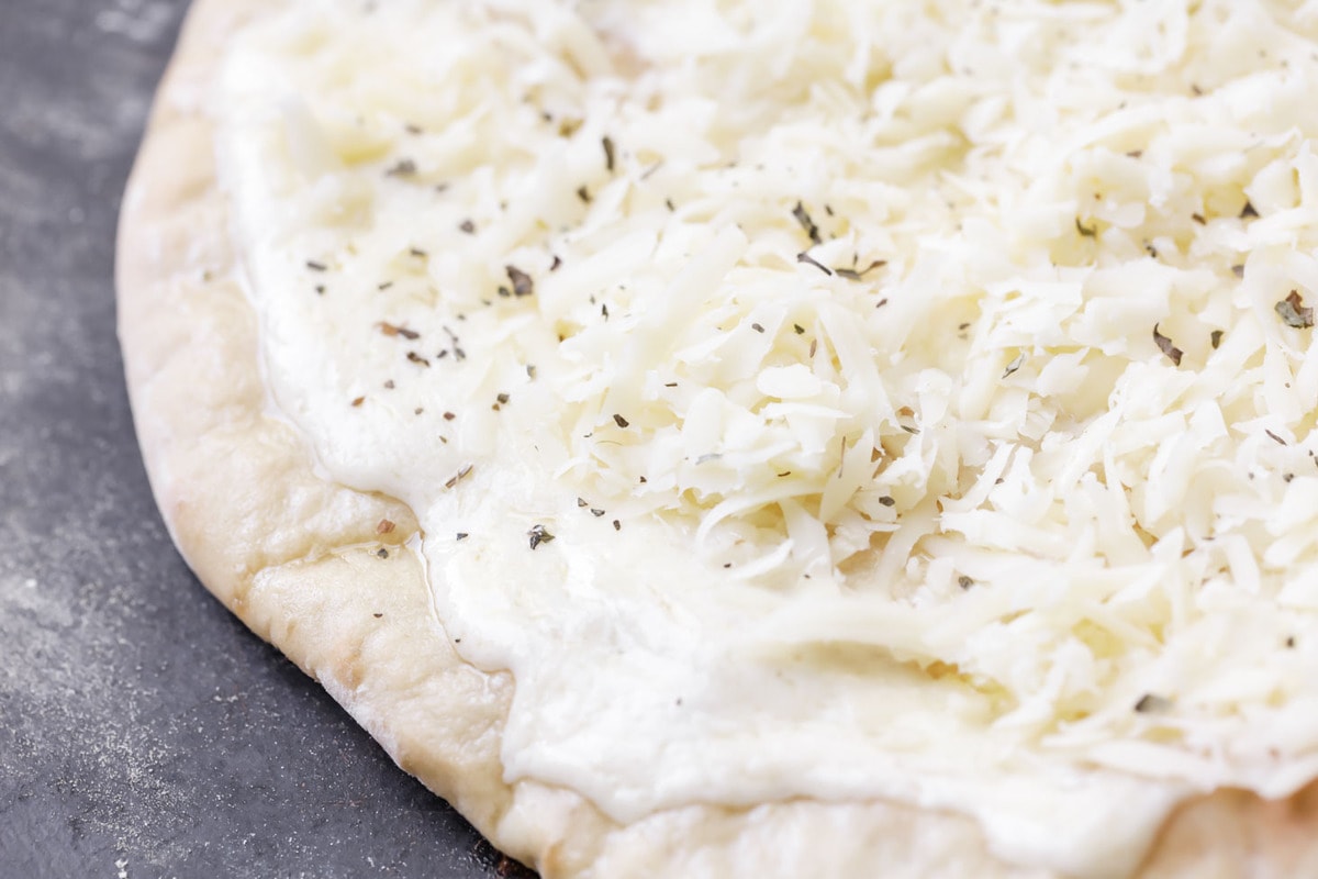 White Pizza Sauce spread on a pizza crust, topped with cheese