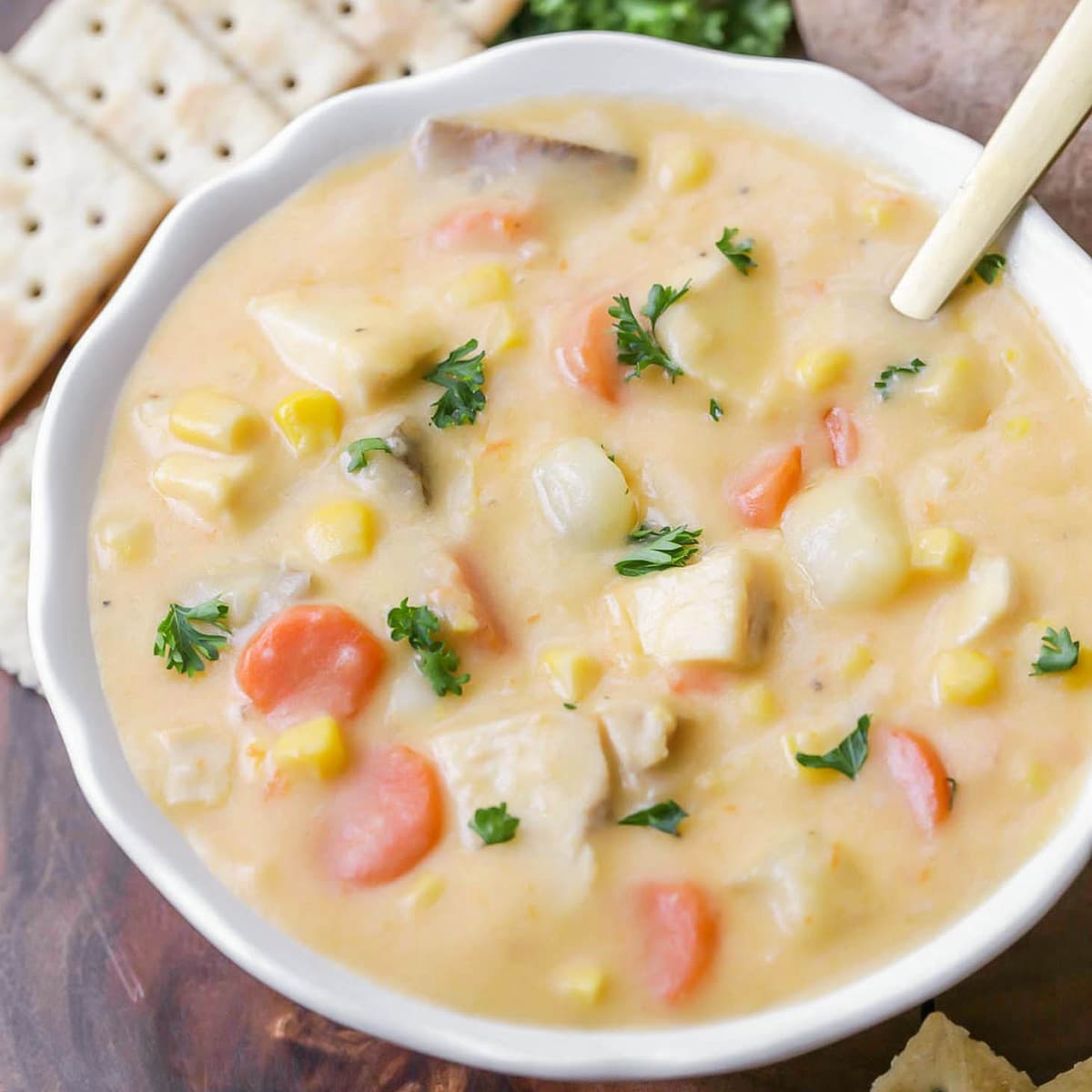 Chicken corn chowder topped with parsley in a white bowl.