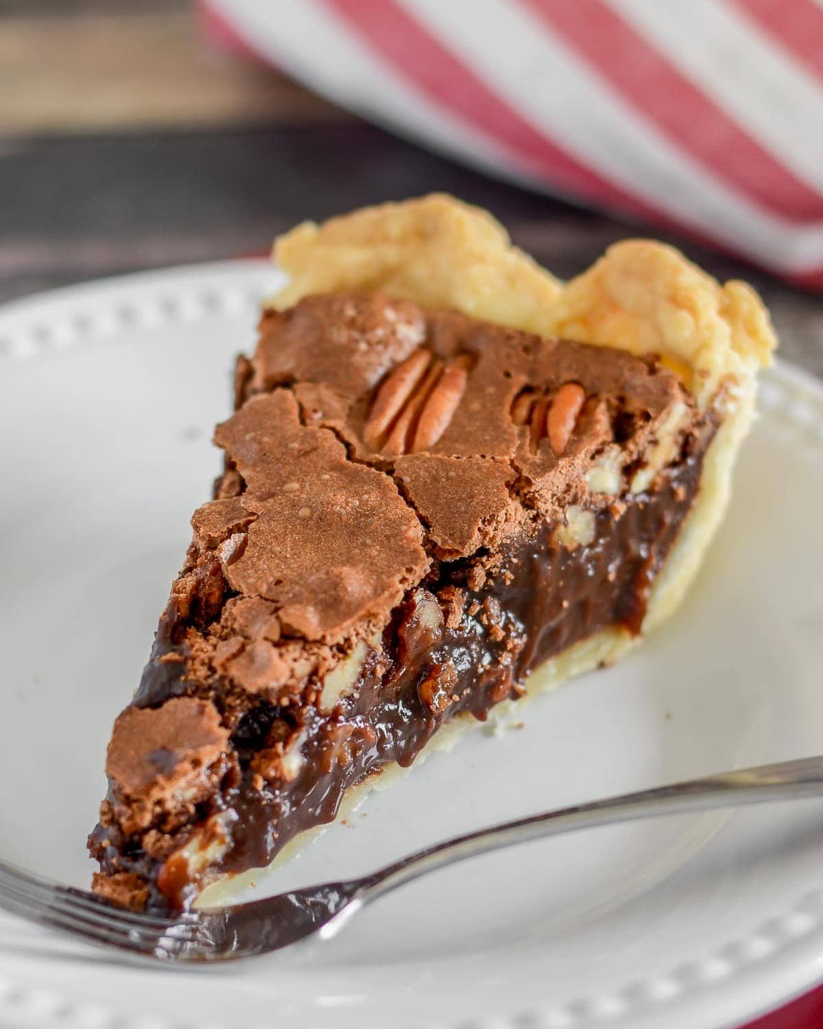 Slice of chocolate pecan pie on a white plate