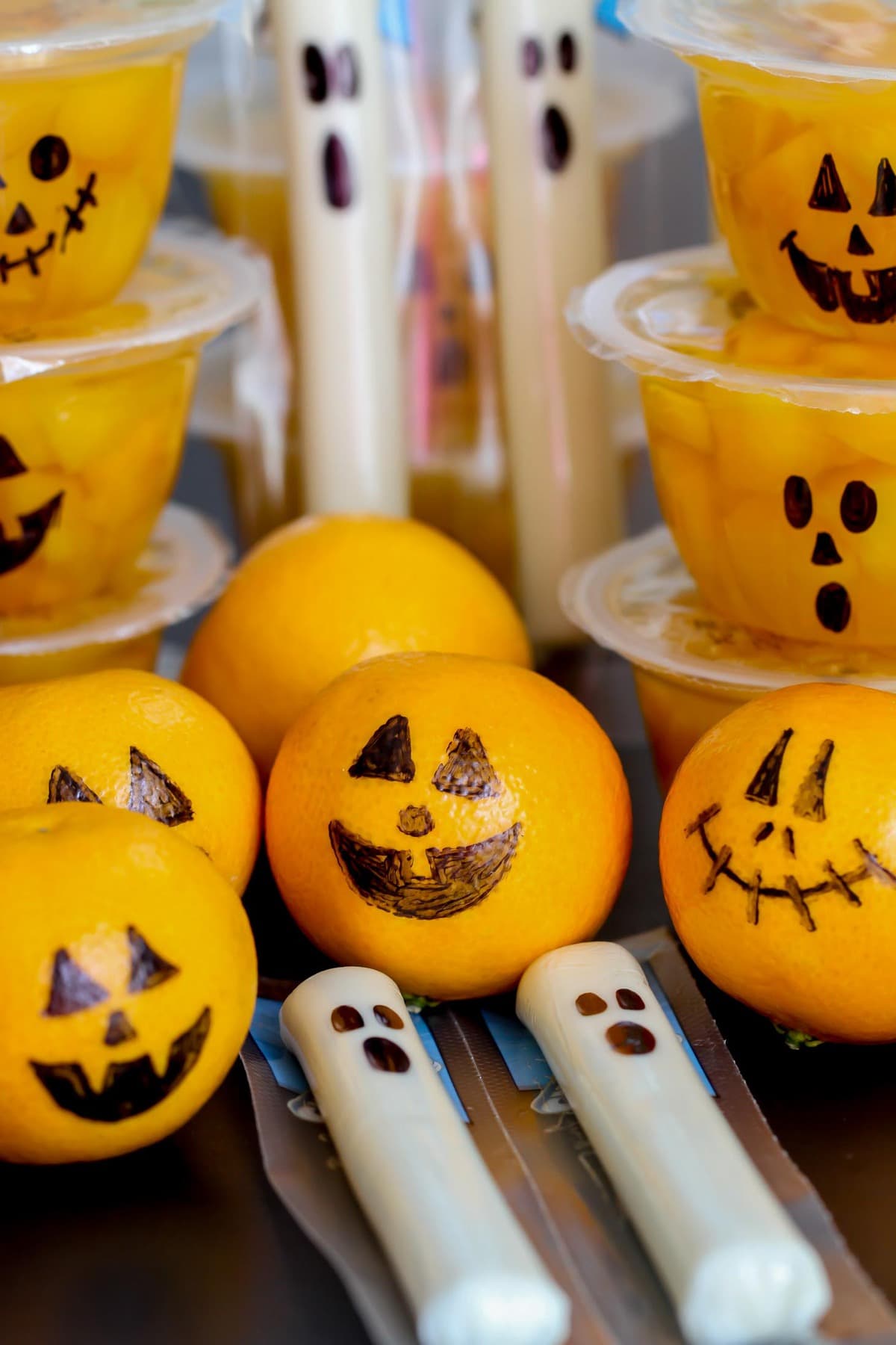 Fruit cups, clementines and cheese sticks with faces