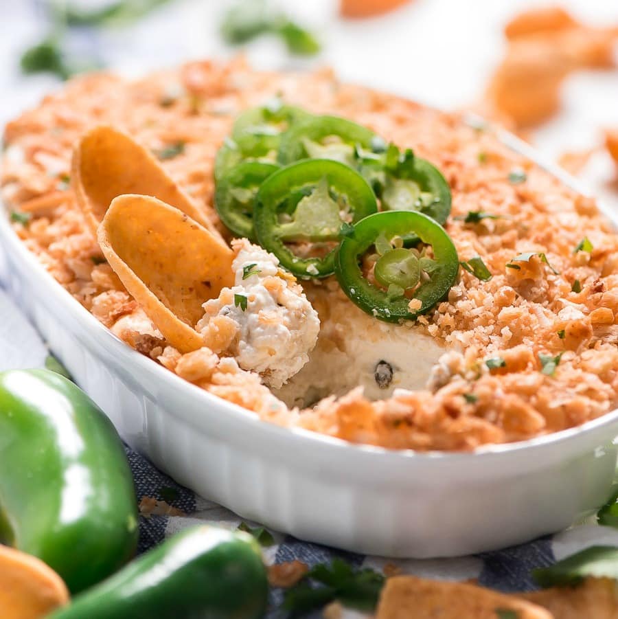 Jalapeno Popper Dip in a white serving dish topped with fresh jalapeno.